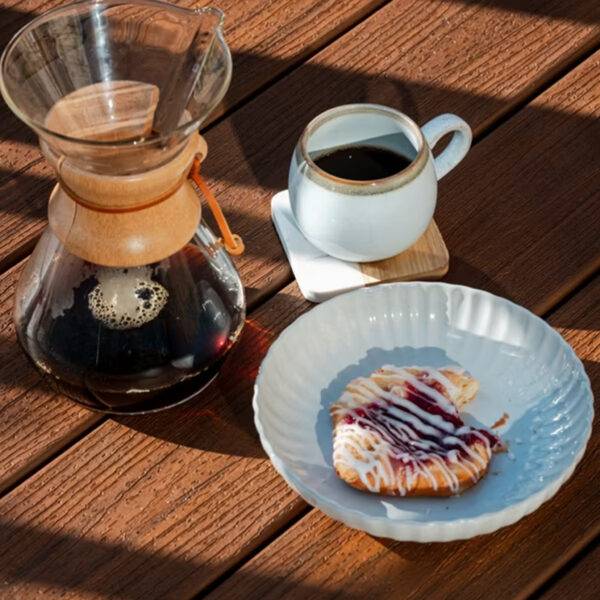 Outdoor Coffee Break on Trex Enhance Basics Cinnamon Cove Decking – A serene moment featuring a steaming cup of coffee and a sweet pastry placed on the textured brown composite deck boards.