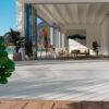Seamless indoor-outdoor transition with Trex Lineage Salt Flat composite decking, extending from a modern living space to a beachfront deck. Light grey tones enhance the open, airy ambiance, showcasing the product’s premium aesthetics and durability against sun and moisture.
