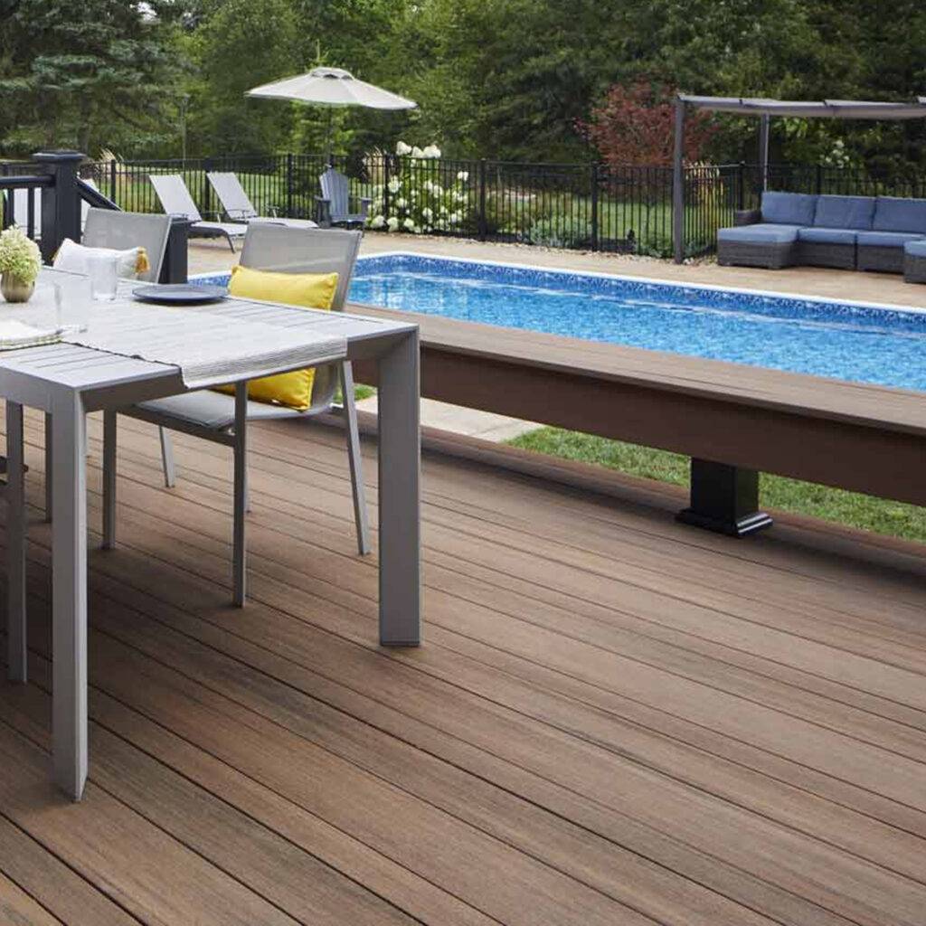 AZEK Multiwidth Decking in Mahogany color, featuring a mix of narrow, standard, and wide-width boards installed around a modern outdoor dining area beside a pool.