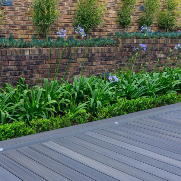 EVA-LAST Infinity Concrete Grey deck installed beside raised garden with brick retaining wall